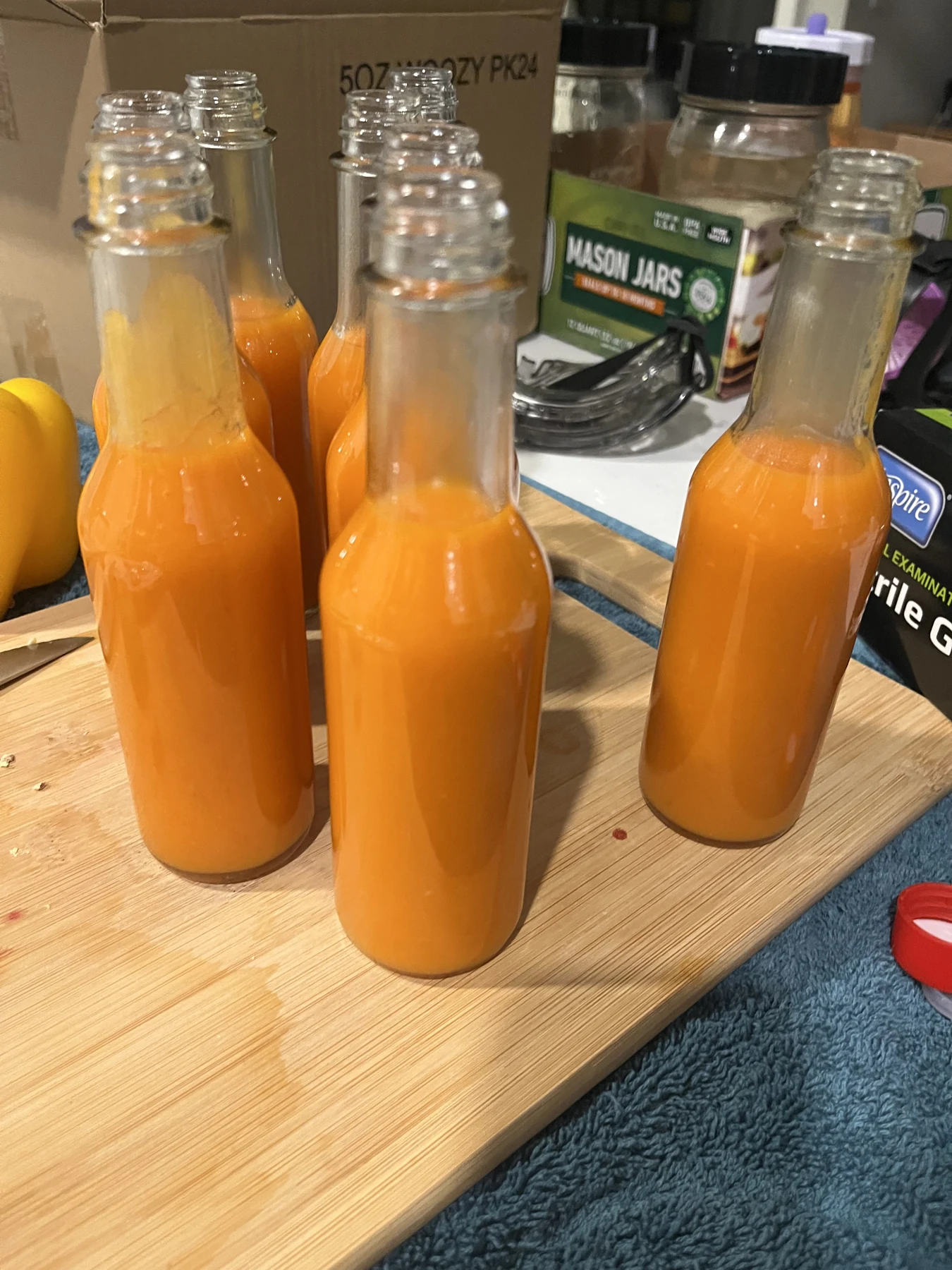 A row of freshly filled homemade hot sauce bottles cooling on the counter.